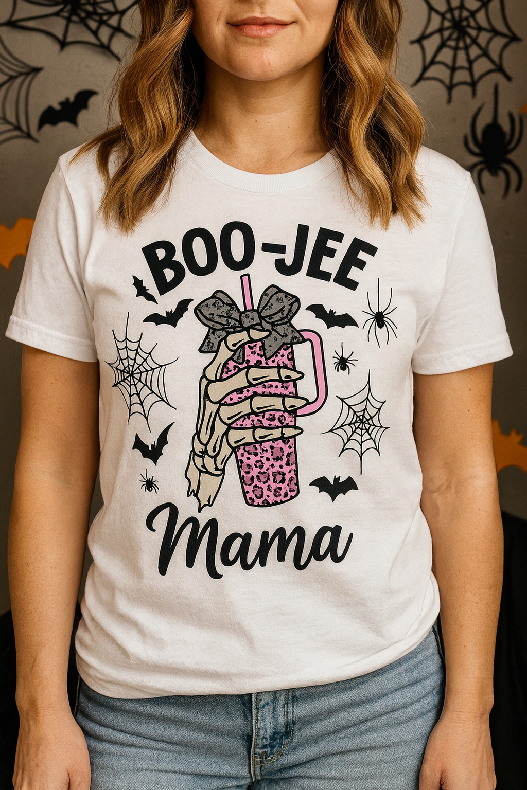 BOO-JEE Mama Halloween unisex tee with skeleton hand holding pink leopard tumbler, bats and spiders, BELLA+CANVAS 3001 worn by a model