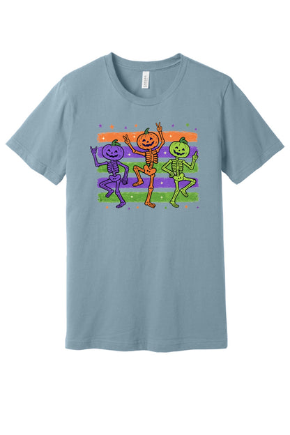 Dancing pumpkin head skeletons Halloween unisex tee in purple orange and green on striped background in Denim