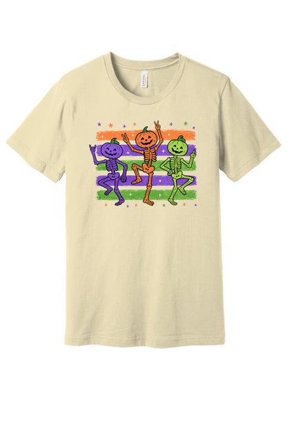 Dancing pumpkin head skeletons Halloween unisex tee in purple orange and green on striped background in Natural