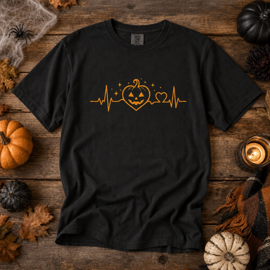 Halloween heartbeat jack-o-lantern pumpkin heart EKG graphic printed on Comfort Colors heavyweight tee, styled flat lay, no model