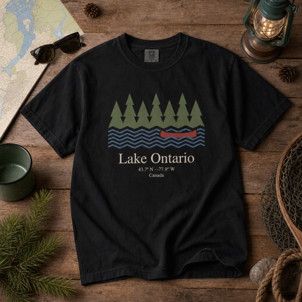 Lake Ontario Canada coordinates vintage canoe and pine trees printed on a Comfort Colors heavyweight tee, styled flat lay, no model