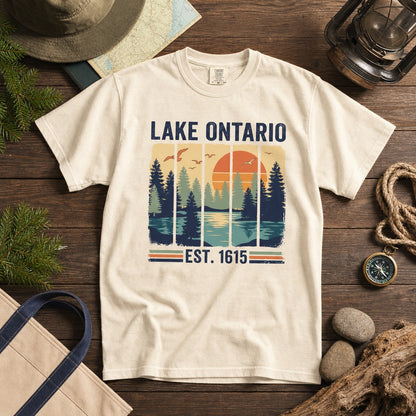 Lake Ontario Est. 1615 vintage pine forest sunset printed on a Comfort Colors heavyweight tee, styled flat lay, no model