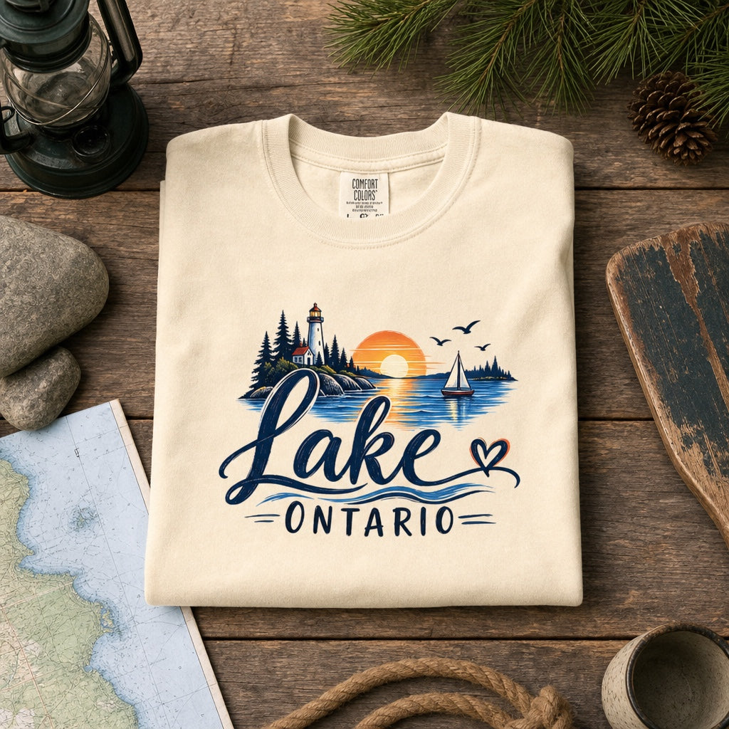 Lake Ontario lighthouse sunset sailboat graphic tee, Lake America protest shirt, DTF printed on Comfort Colors 1717, styled flat lay, no model