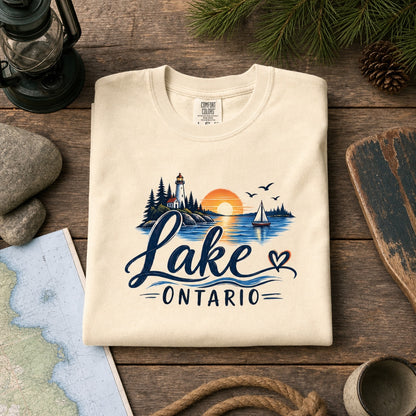 Lake Ontario lighthouse sunset sailboat graphic tee, Lake America protest shirt, DTF printed on Comfort Colors 1717, styled flat lay, no model