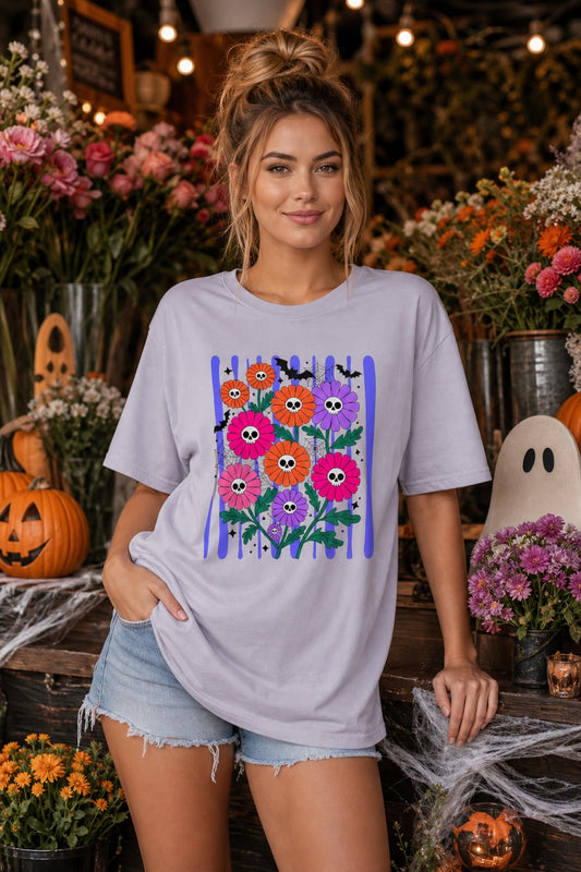 Skull gerbera daisy bouquet with bats and spider webs Halloween graphic tee in orange pink and purple worn by a model