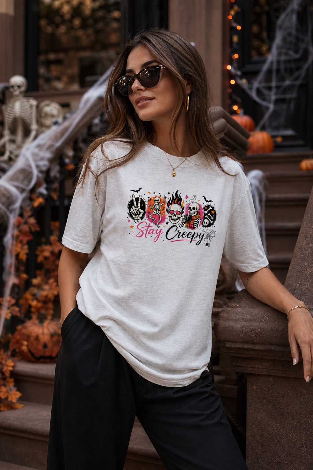 Stay Creepy Halloween graphic tee with dancing skeletons flaming skull and rock hand print worn by a model