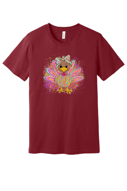 Colorful cartoon girl turkey with bow and tie-dye swirl feathers printed on a unisex Thanksgiving tee in Cardinal