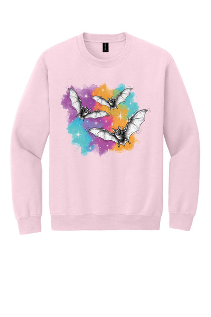 Gildan 18000 crewneck sweatshirt with three sketch-style flying bats over a watercolor purple teal orange sparkle Halloween print in Light Pink